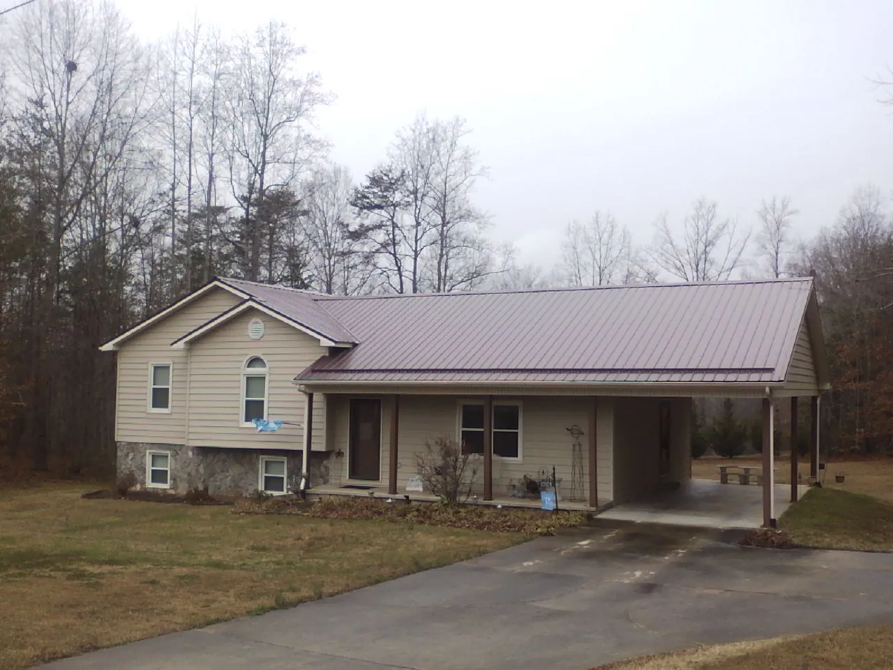 Burgundy metal roof on a tan split level home with an attached carport in Monticello
