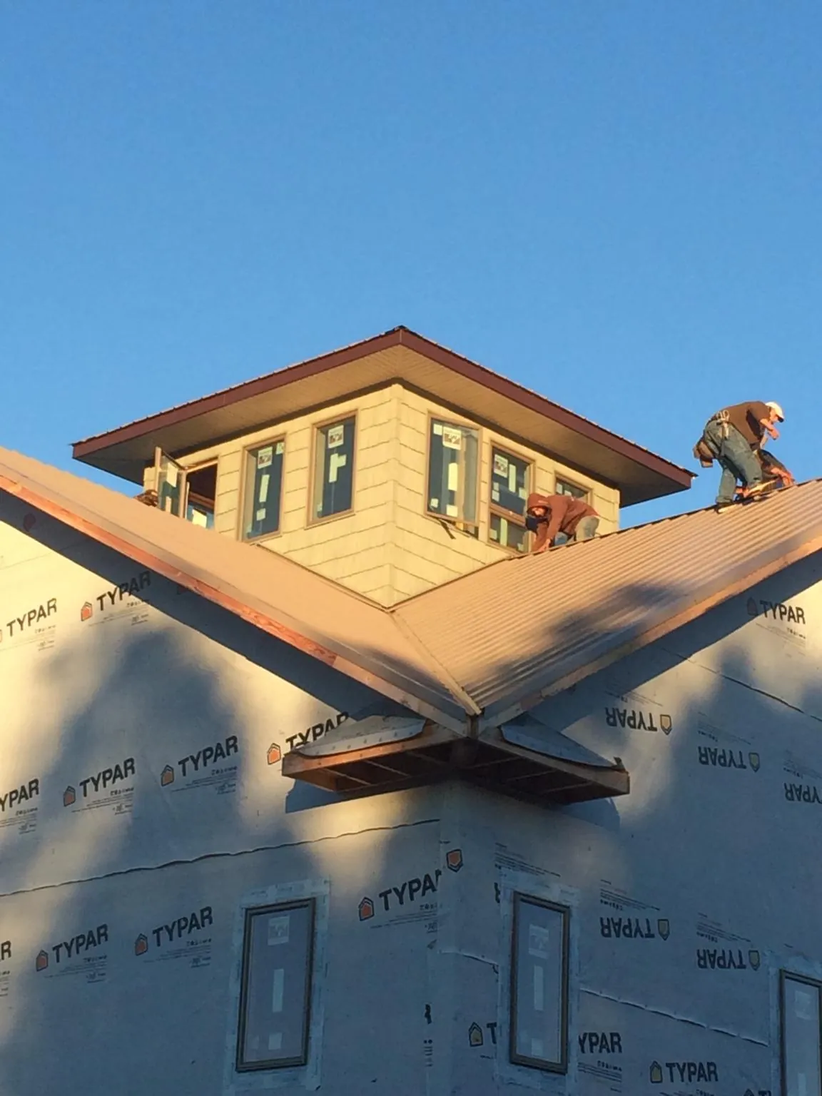 Roofers working around a rooftop cupola on a new metal roof at sunset — Roof Waterproofing in Monticello by Roofing Brothers